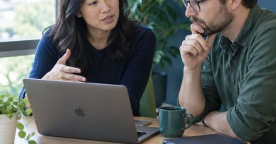 Startup founder and engineering lead discussing an AI-augmented development plan over a laptop